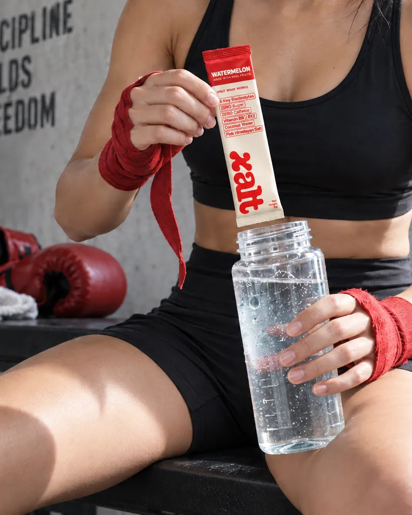 Pouring a sachet into a water bottle on a gym bench